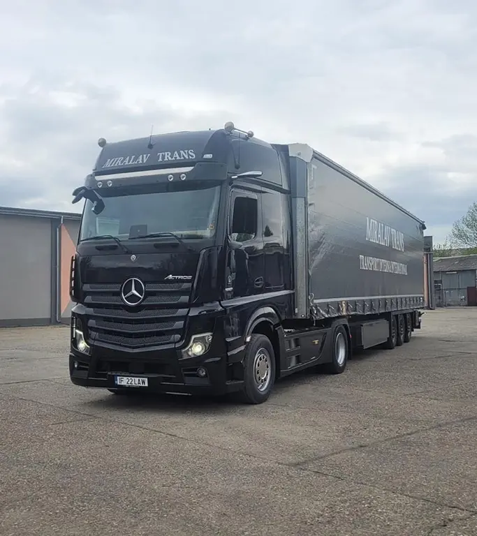 Camion Mercedes-Benz modern si semi-remorca cu prelata inscriptionata cu numele companiei